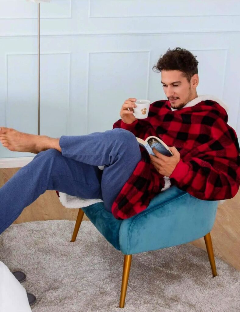 un homme qui porte un sweat plaid motif tartan qui est en train de lire un livre 